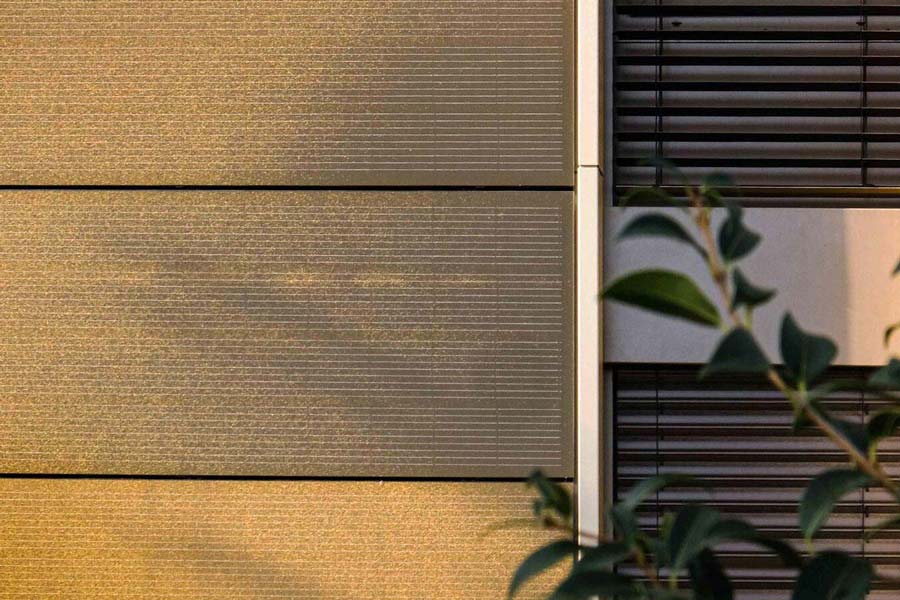 Glasfassade in Wunschfarbe mit Solarpanelen dahinter - Plansecure Safe-Homes